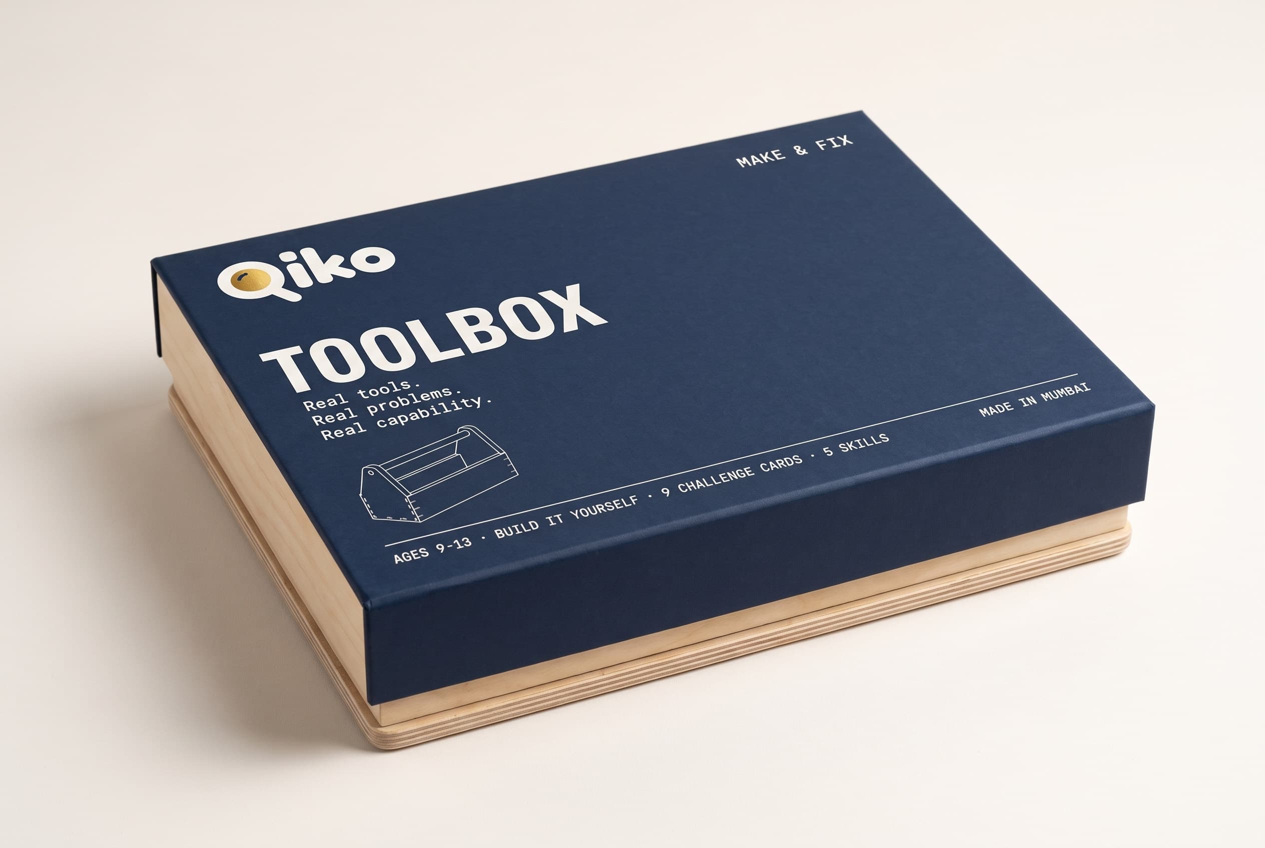 The closed Qiko Toolbox box: a deep navy matte lid on a birch plywood tray.
