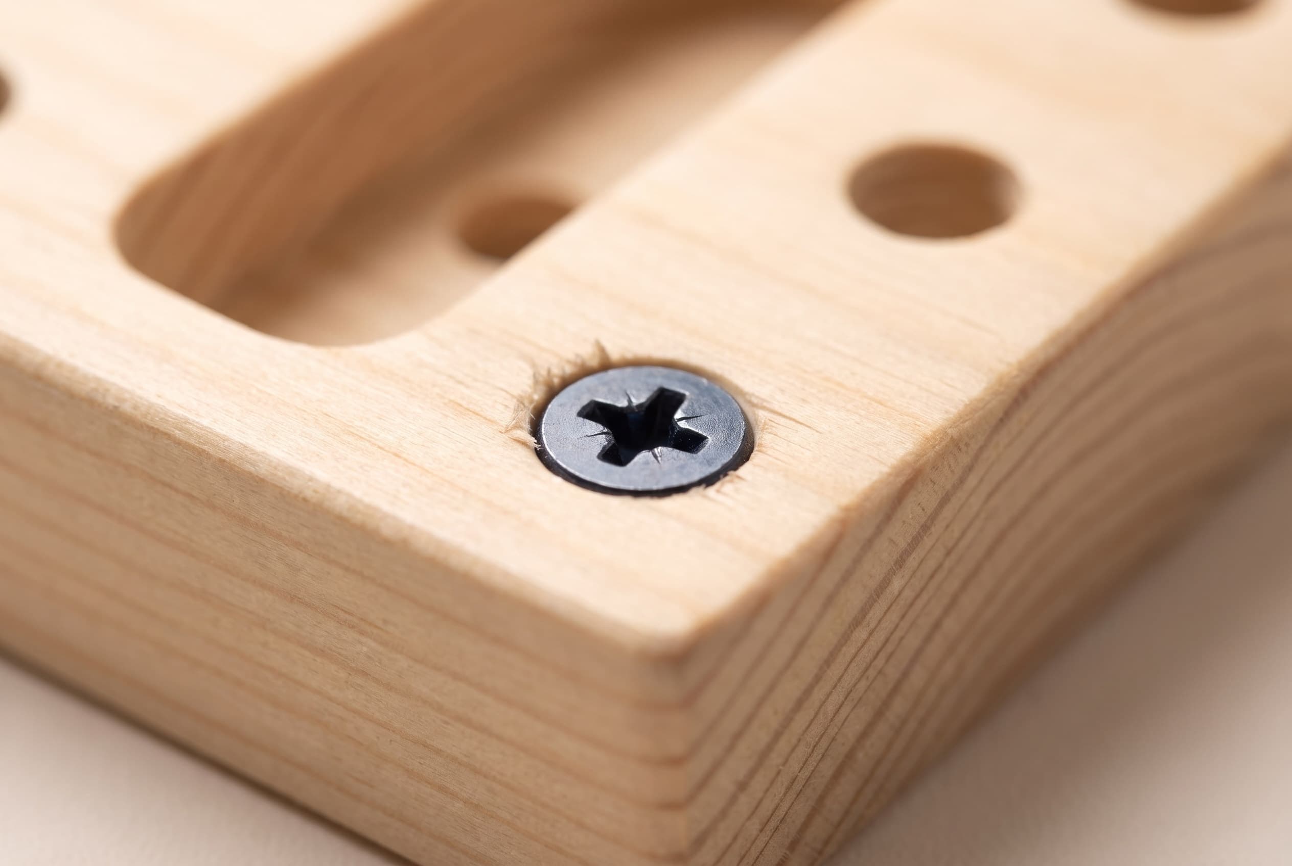 Macro of a single screw seated flush in the pine screw block, its head sitting down onto the surface.